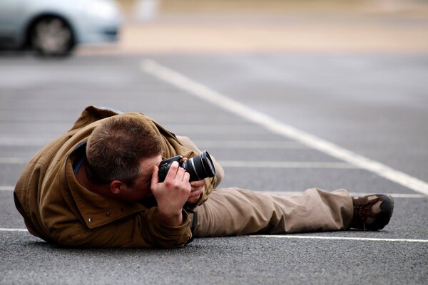 Homme prenant des photos en position couchée