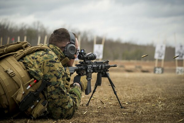 Un homme en uniforme militaire avec une arme à feu se trouve sur le sol