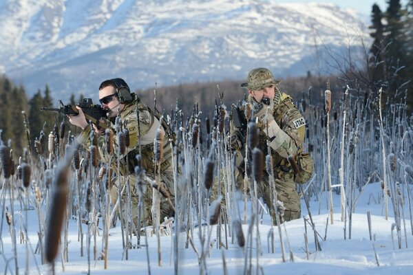 Soldiers with weapons in winter. Mountains