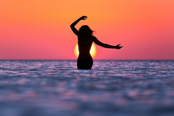 Silhouette d une jeune fille sur la mer au coucher du soleil