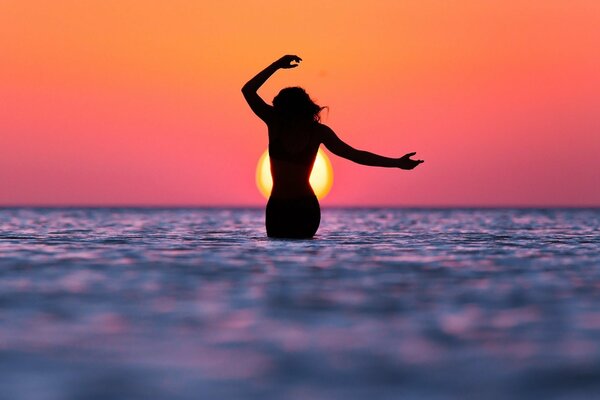 Silhouette di una ragazza sul mare al tramonto