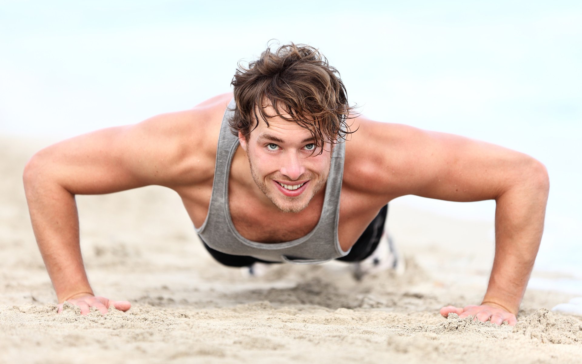 hombre flexiones músculos sonrisa playa arena