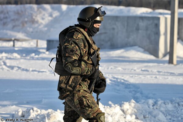 A special forces soldier with a weapon in uniform against the background of snow