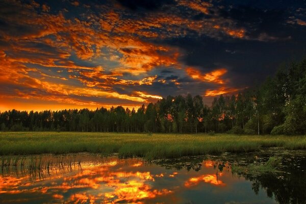 A fiery sunset is reflected in the lake