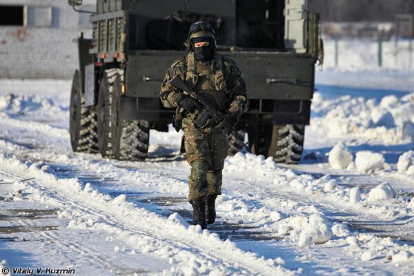 Un comando ruso con un arma en el fondo de un camión en invierno