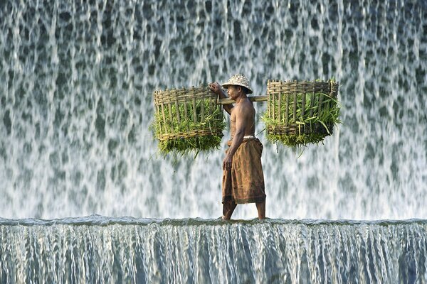 Un homme marche le long d une cascade et porte un fardeau