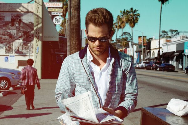 Chris Pine, der auf der Straße eine Zeitung liest