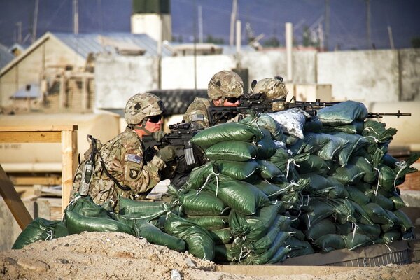 Soldiers with weapons hid behind a barricade