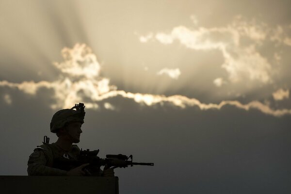 Soldado en el puesto con armas contra el cielo nocturno