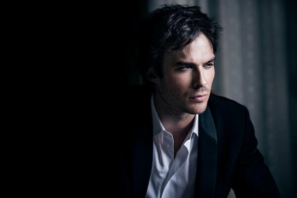 A serious man in a jacket on a black background