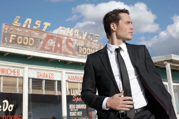 Taylor Kitsch en traje en el fondo de la gasolinera