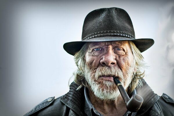 Hombre viejo con tubo en la boca y en el sombrero