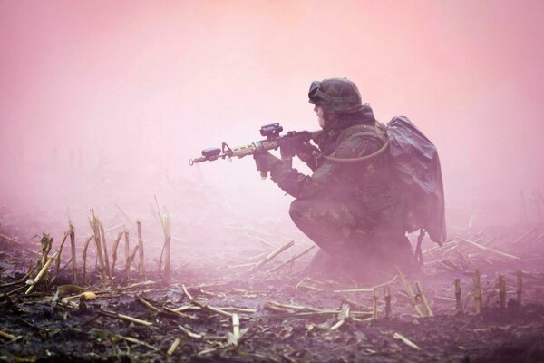 Soldado con armas en la niebla en el campo