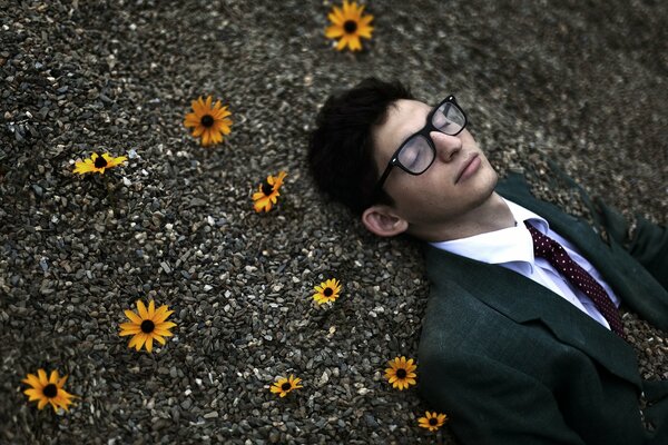 A man lying in stones with orange flowers