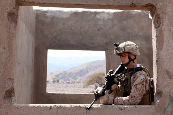 A soldier with a gun on the background of a wall