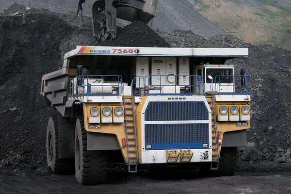 Dump truck in the process of working in coal and dust