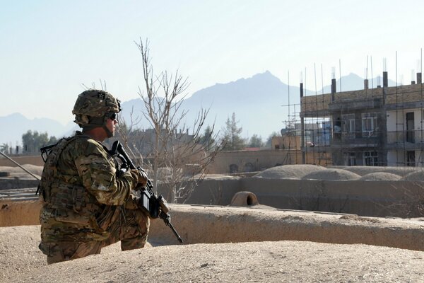Солдат с оружием на фоне безлюдной местности
