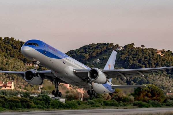 El avión en el fondo de las montañas boscosas se levantó del Suelo