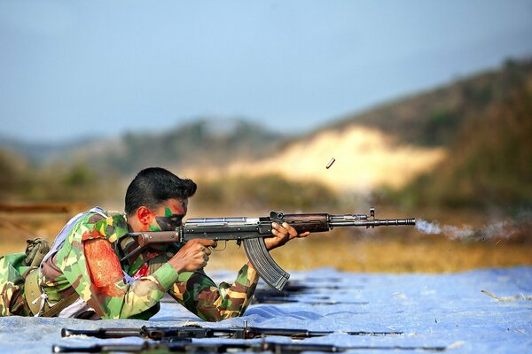 A soldier when shooting lying down with a weapon