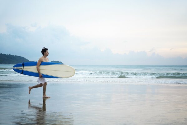 Mec sur la plage avec une planche de surf