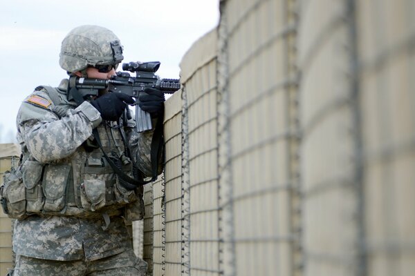 Un soldado con un arma cerca de la pared