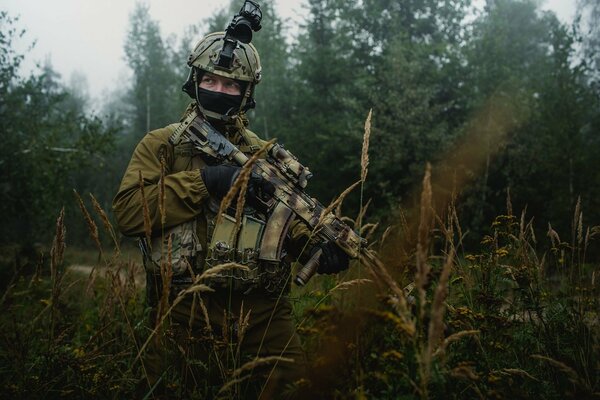 Żołnierz z karabinem Kałasznikowa w lesie