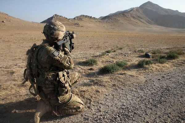 A soldier with a machine gun in the desert took aim