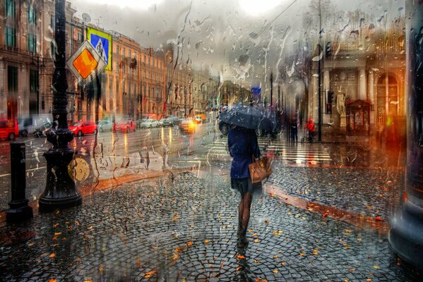 A girl with an umbrella hurries home along the city paving stones