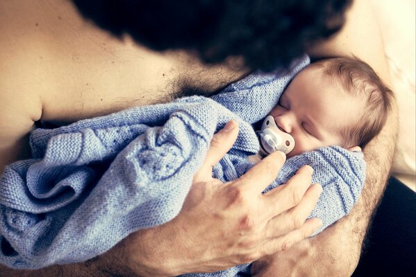 A man with a baby in his arms who is sleeping