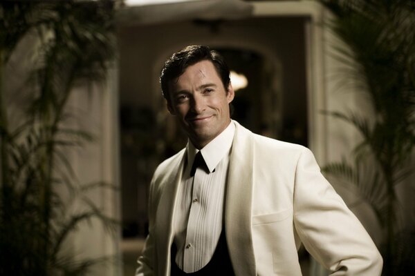 Hugh Jackman sonríe con un traje blanco