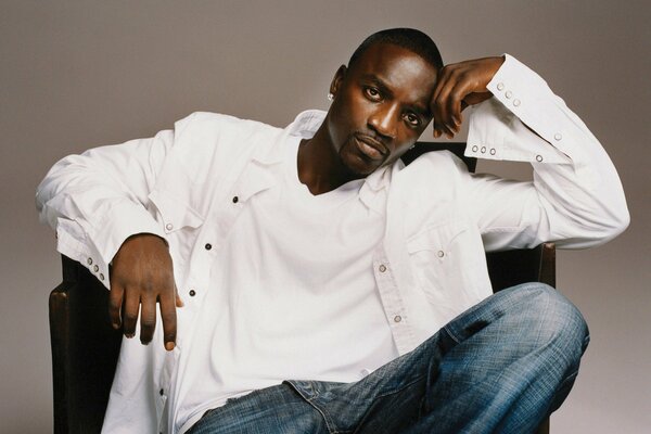 Cantante Akon en una camisa blanca en una silla