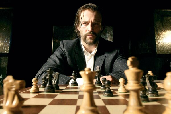 The actor is sitting at the chessboard