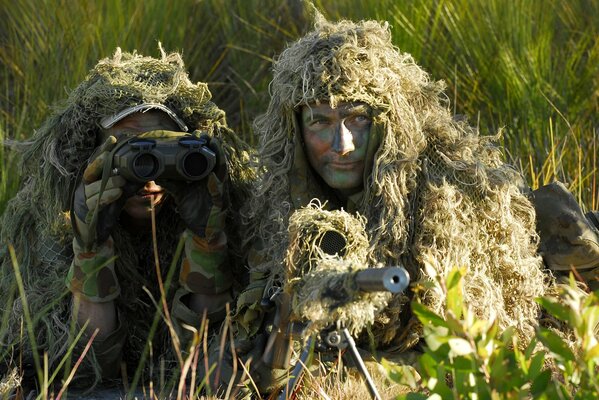 Dos hombres francotiradores tendidos en una emboscada con un rifle de francotirador