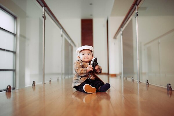 The baby is elegantly dressed sitting on the floor