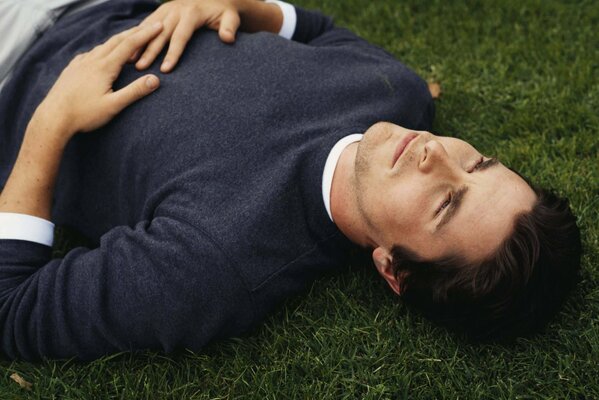 Мечтщий мужчина лежащей на газоне