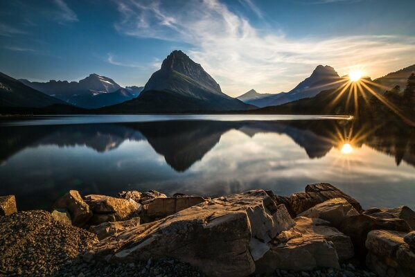 Puesta del sol en el fondo de las montañas y el lago