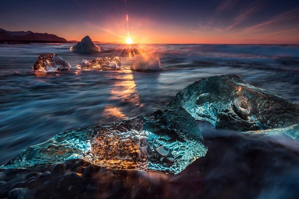 Sunset over icy rocks in the water