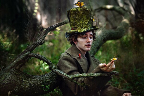 Mężczyzna w kapeluszu w lesie z motylami