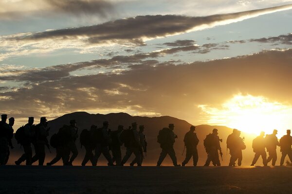 Los soldados en el fondo de la montaña van al atardecer