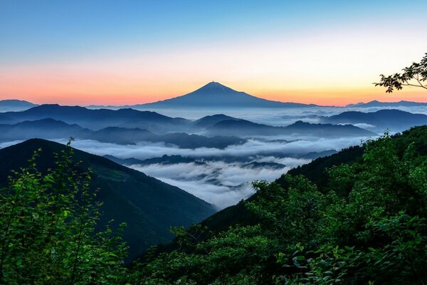 Brouillard descend des montagnes sur fond de coucher de soleil