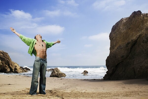 A man stands against the background of the sea and rocks