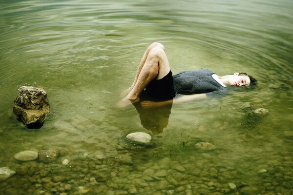 Il ragazzo si trova sulle rocce in un lago con acqua verde