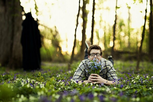 Ein Mann liegt mit einem Blumenstrauß auf dem Rasen