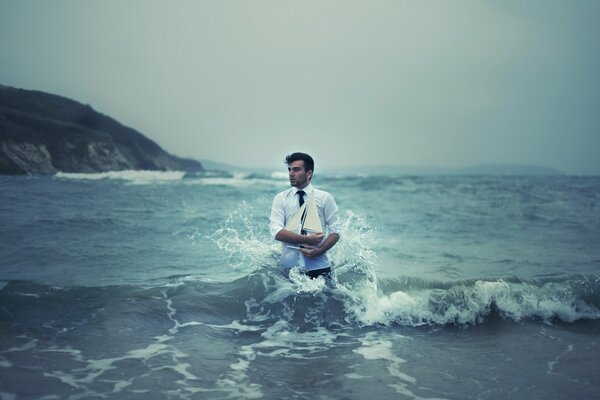 A man stands in the sea with a ship