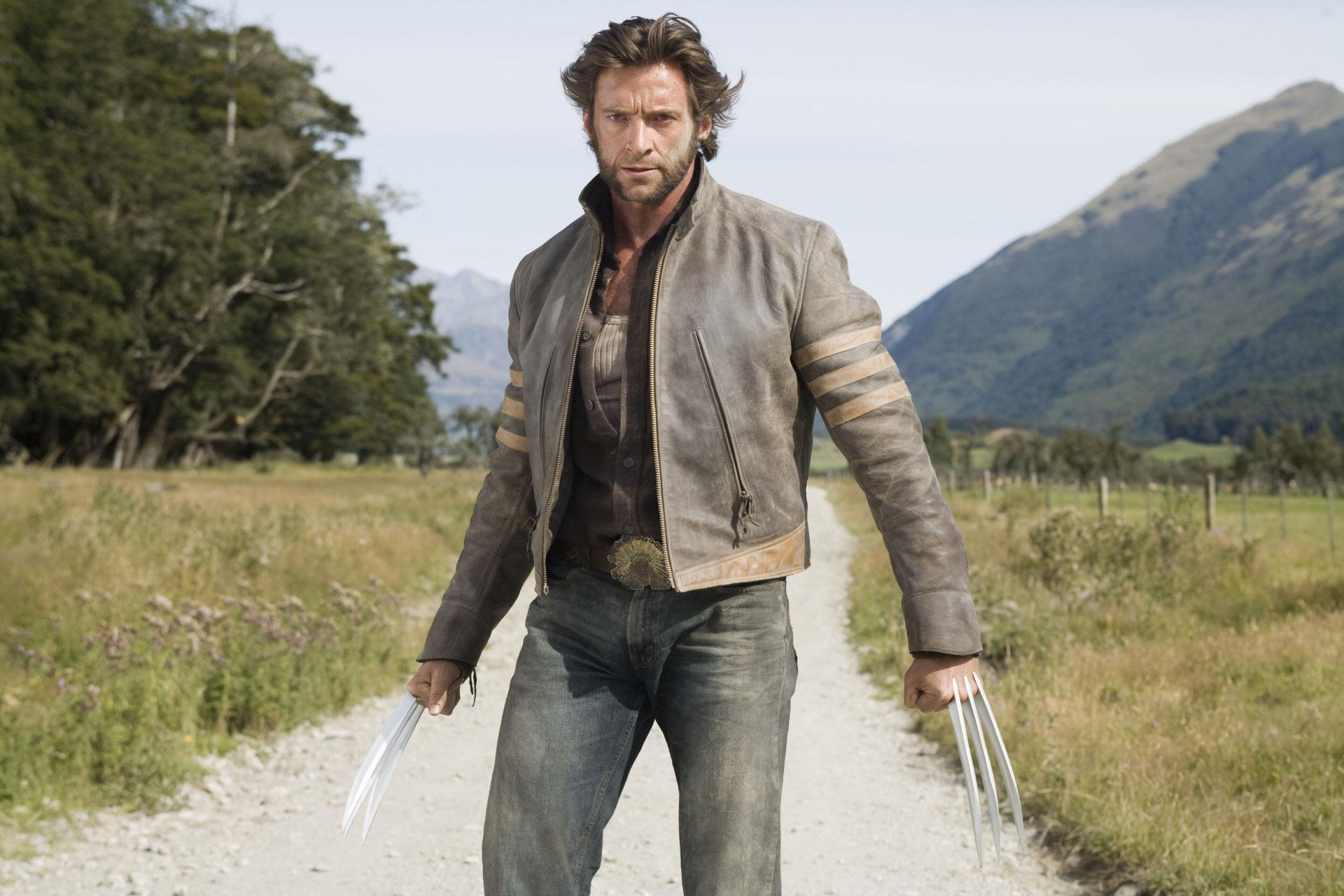 hugh jackman wolverine james logan minet acteur homme héros mutant x-men x-men couteaux griffes pointes regard sable poussière veste montagnes arbres ciel