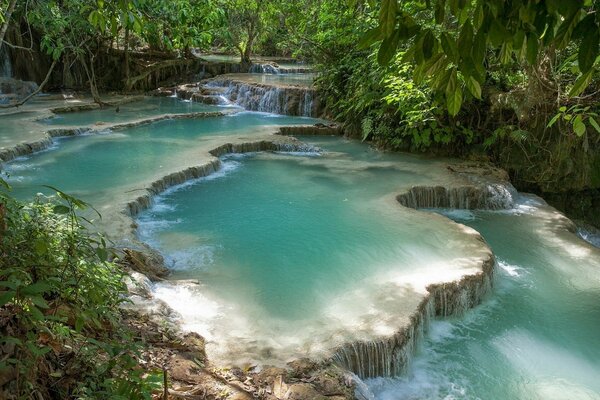 Ein See mit einem kleinen Wasserfall und Bäumen