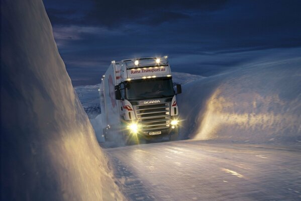 Biała ciężarówka przedzierająca się przez lód na tle nocnego nieba