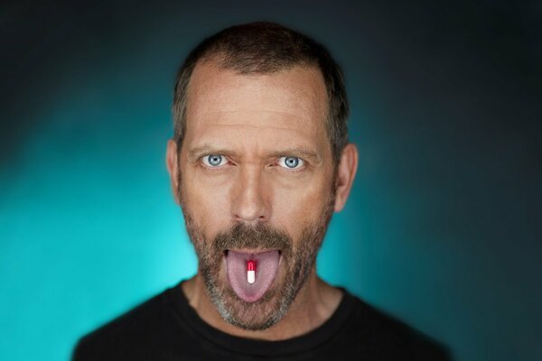 Hugh Laurie mit einer Pille auf der Zunge