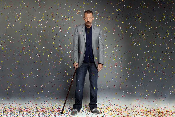 Hugh Laurie stands with a stick for support