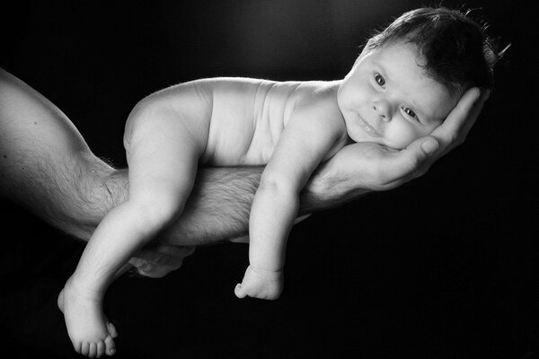 Il bambino giace sulla mano di papà